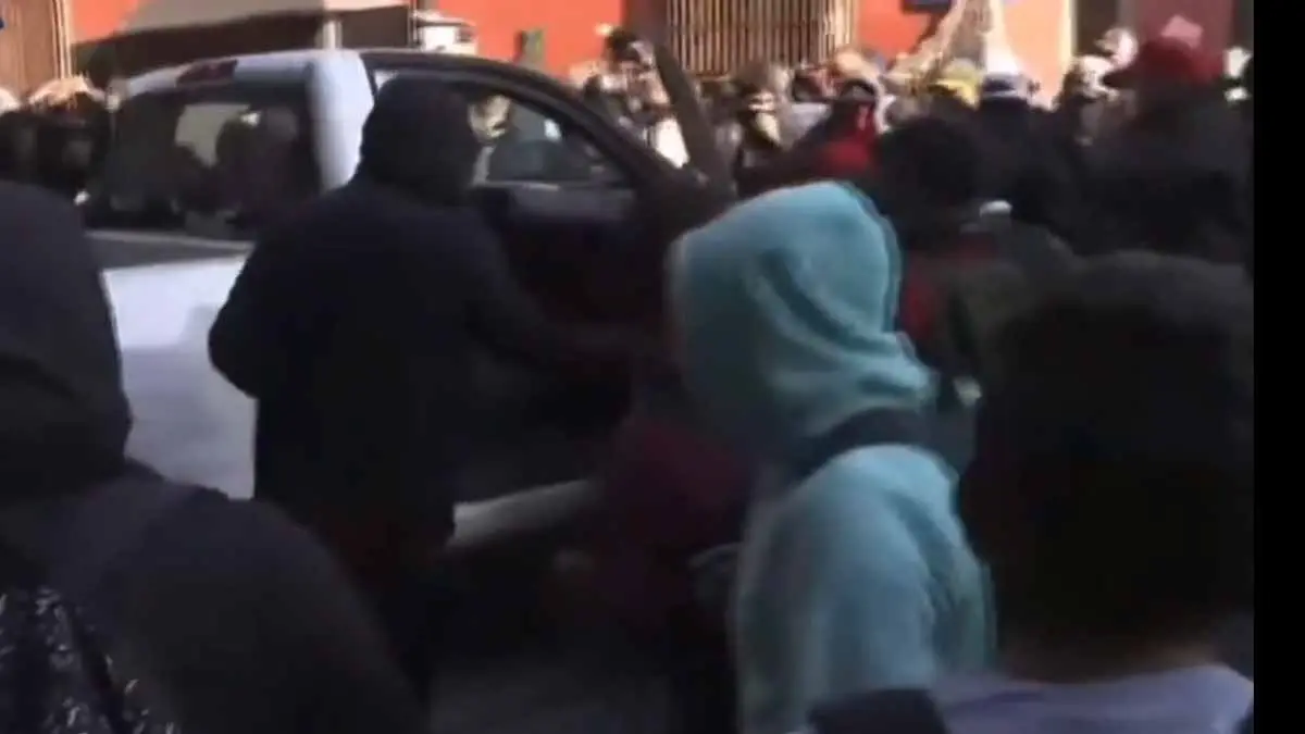 VIDEO | Padres de normalistas de Ayotzinapa derriban puerta de Palacio Nacional con auto de la CFE, en plena Mañanera